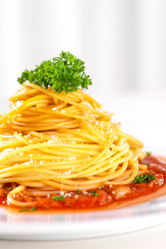 Close-up of spaghetti with tomato sauce, garnished with herbs and cheese.