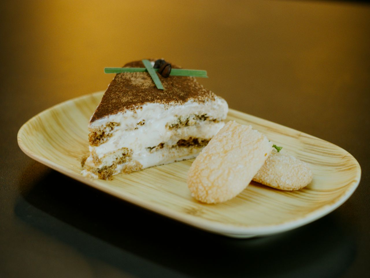 Mastering the First Impression: Your intriguing post title goes here A close-up shot of a delectable tiramisu slice and ladyfingers on a wooden plate.