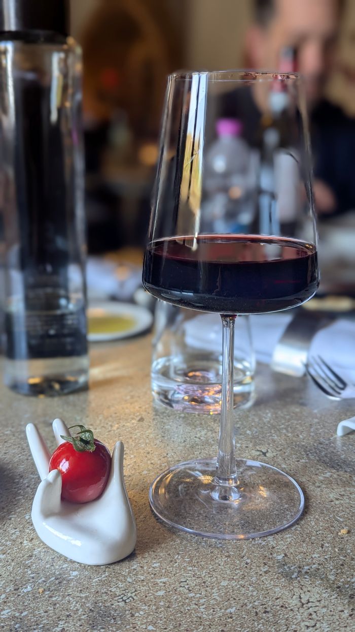 A sophisticated still life featuring a wine glass and cherry tomato in an elegant dining setting.
