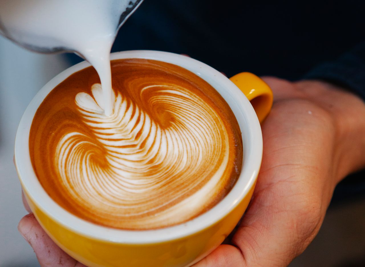 The Art of Drawing Readers In: Your attractive post title goes here Unrecognizable professional barista pouring milk from pitcher into yellow cup with latte with creative pattern while working in coffee house